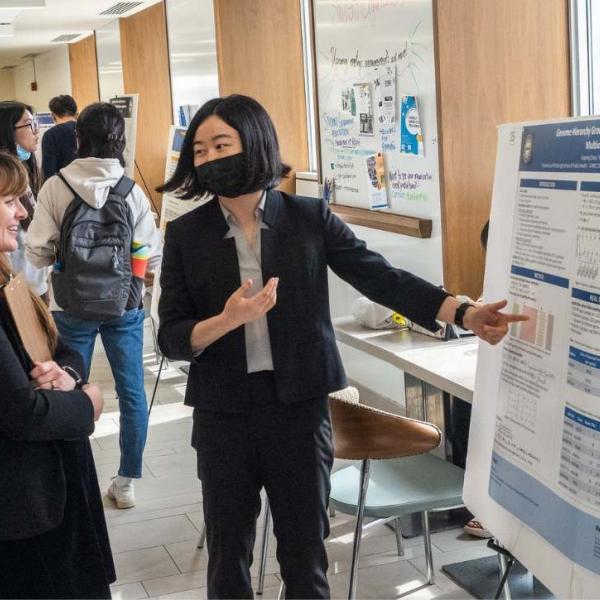 student presenting poster to faculty member