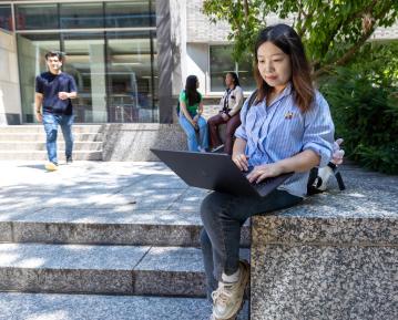 student on computer outside