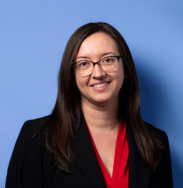 Meredith Hughes wearing a jacket in front of blue background